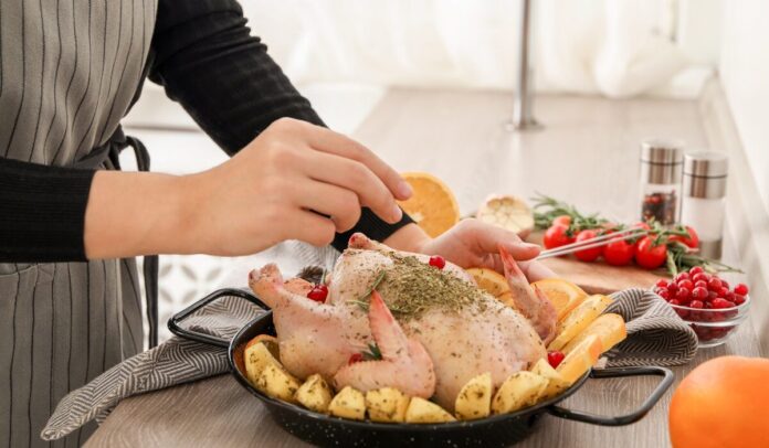 Woman,Cooking,Chicken,With,Orange,And,Potato,Slices,At,Wooden